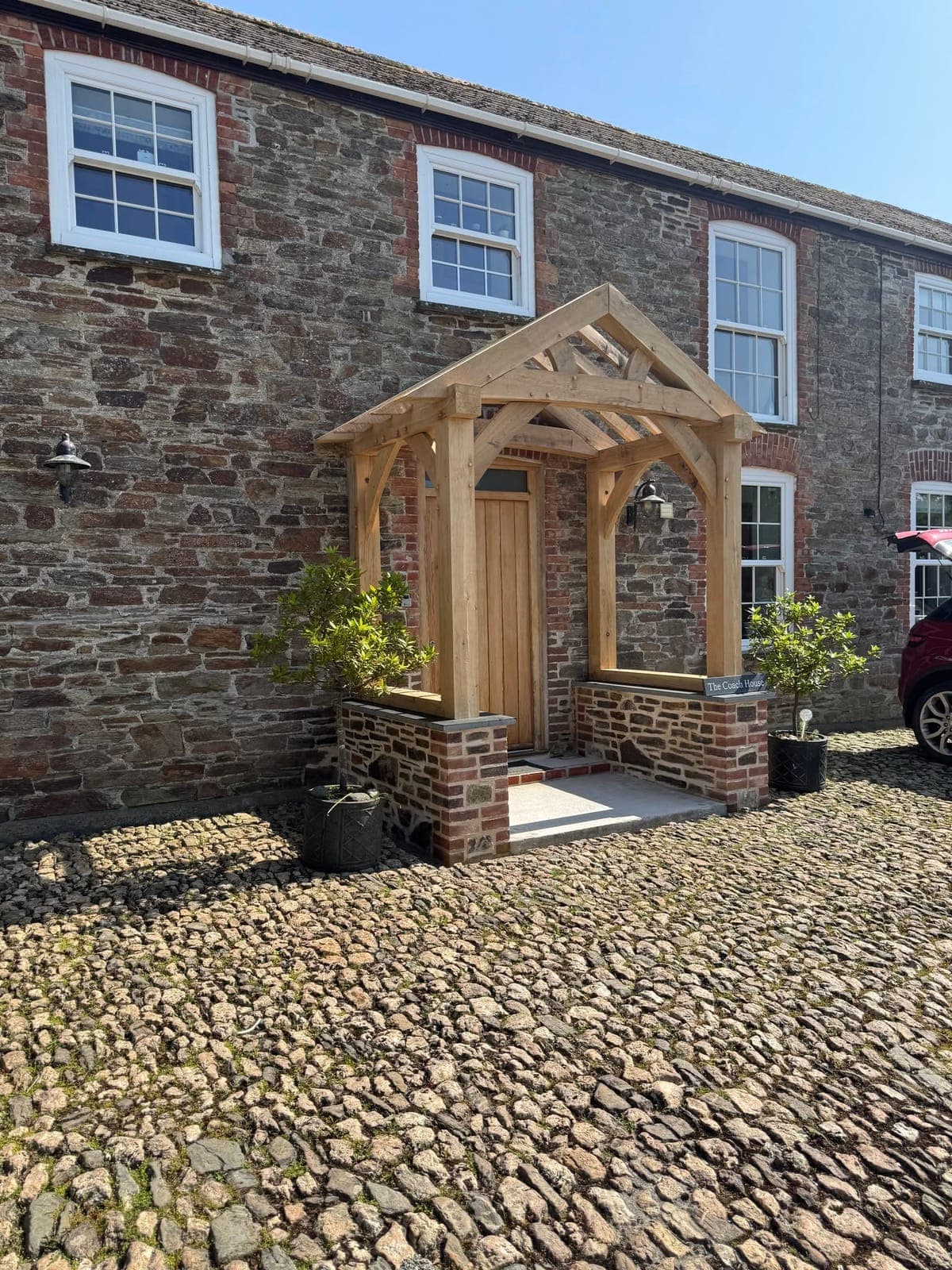 Bespoke oak-framed entrance porch on a traditional stone cottage in Cornwall, built by Dover & Co Construction